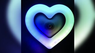 Nipple in the middle of a small kawaii heart ring light with swirling RGB colors
